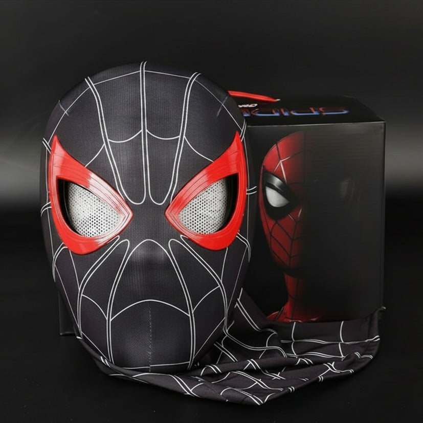 A Spider-Man-themed headgear mask with a black and red design is shown next to its black packaging box on a dark background. The mask features white web patterns and red eye cutouts.