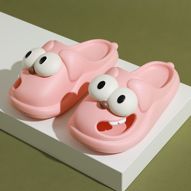 Pink cartoonish shoes with googly eyes on a white platform against a green background