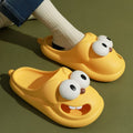 Yellow cartoon-style slippers with white eyes and a brown nose on a green background.