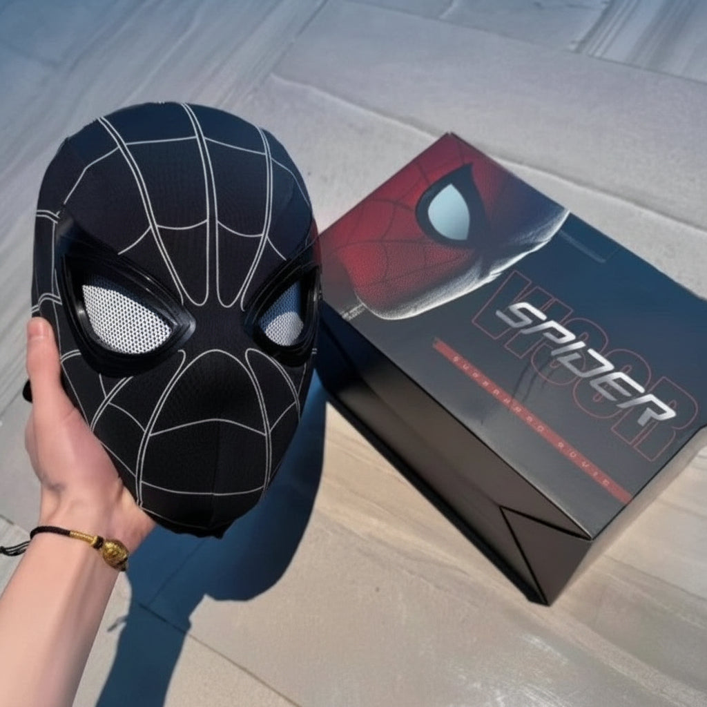 Black spider-themed mask held by a hand with a Spider-Man box in the background.