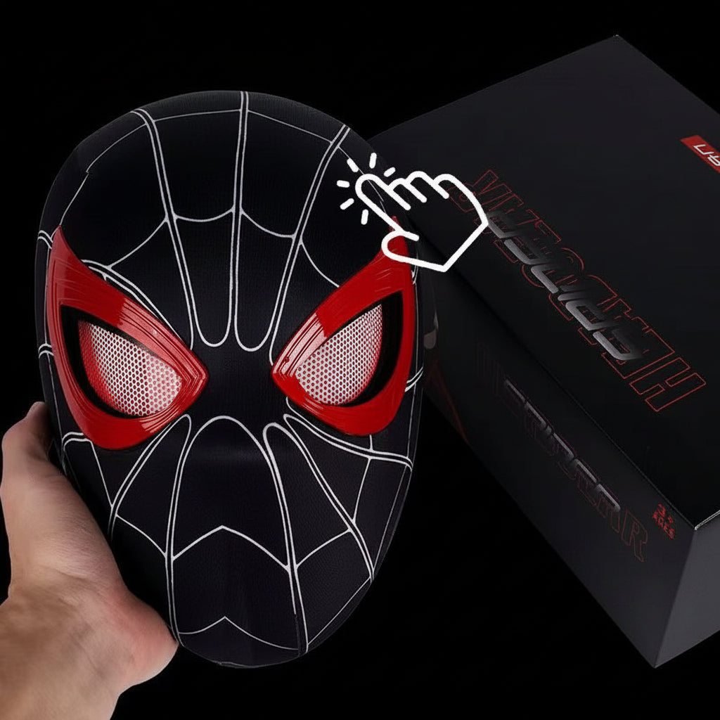 A black and red Spider-Man-style mask being held in a hand and a black product box in the background. The mask has white web lines and red eye areas, and the box shows partial red lettering.