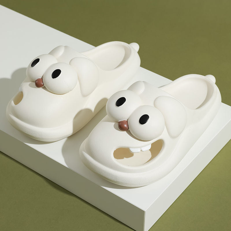 Two white Big Eye Fluffy slippers with black eyes and pink beaks on a white platform against a green background.
